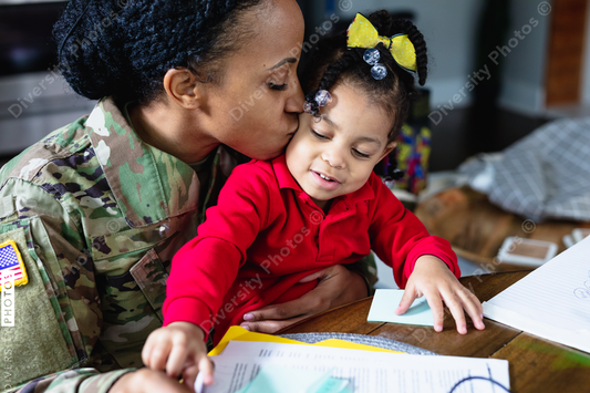 Black soldier mother kisses daughter while working from home