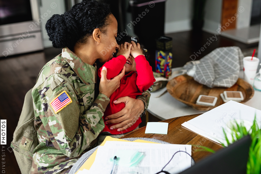 Black soldier mother kisses daughter while working from home
