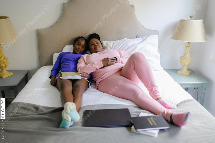 Mother and teenage daughter lying on bed