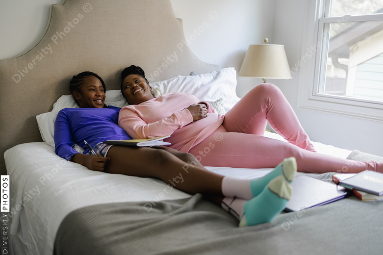 Smiling mother and teenage daughter lying on bed