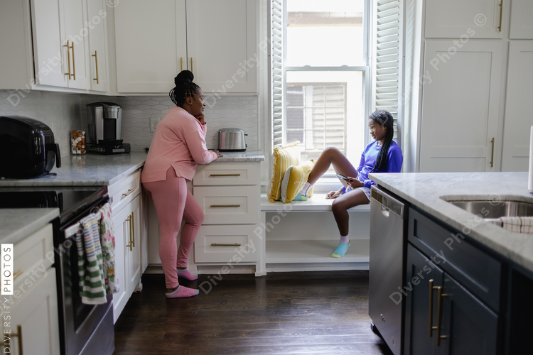 Mother and teenage daughter talking in kitchen