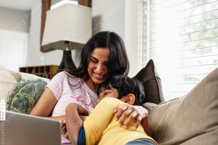 Indian mother and son cuddling on couch at home