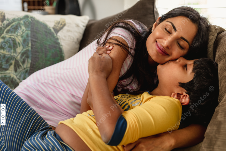 Smiling Indian mom embracing son at home