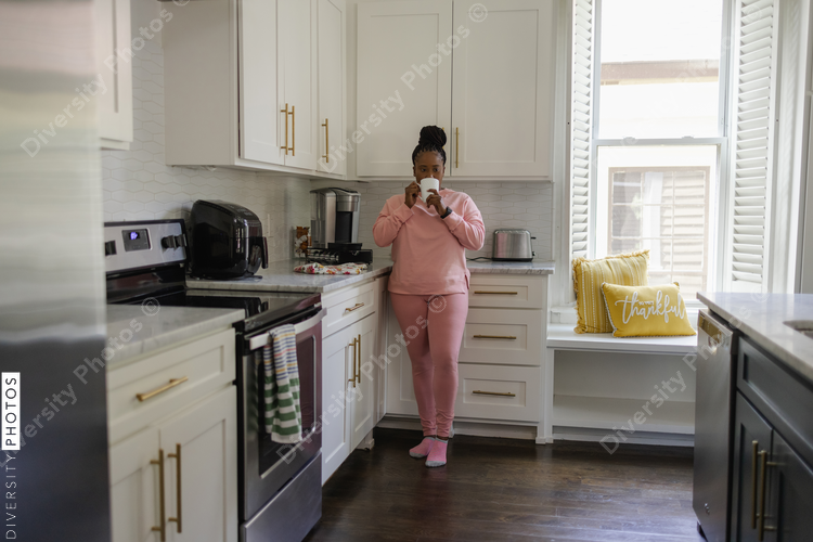 Woman drinking from mug in kitchen
