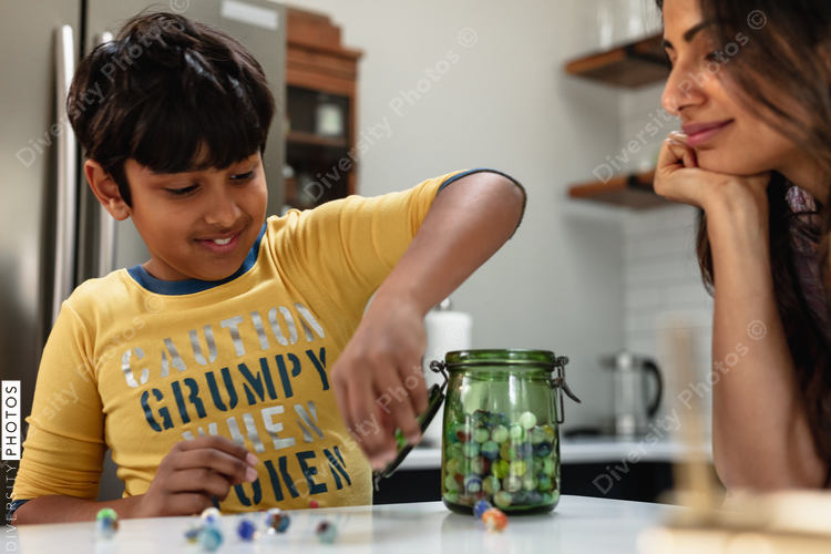 Indian boy plays with marble toys, mom enjoys watching son happy