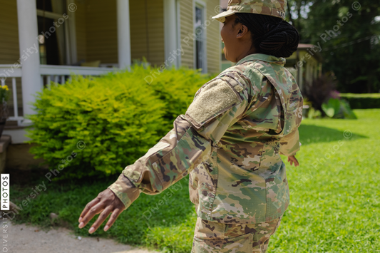 African American Military woman in camouflage uniform walking on front yard with arms outstretched