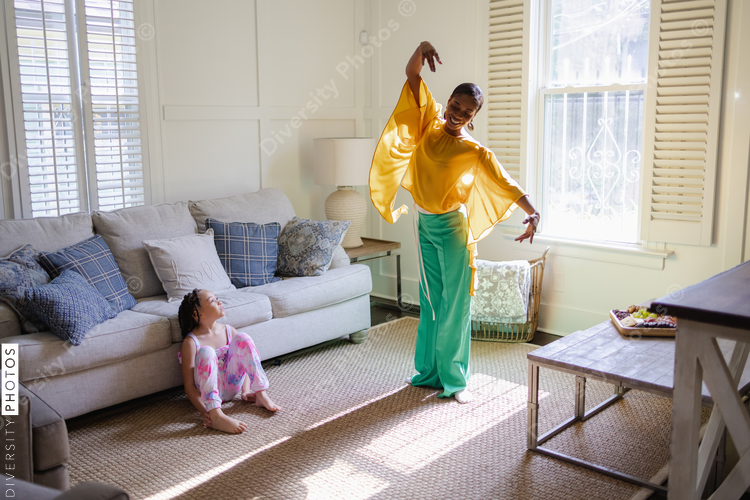 Daughter looking at mother dancing in living room