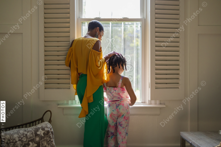 Mother and daughter looking through window in living room