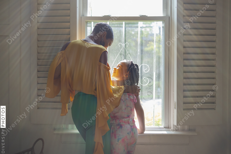 Mother and daughter standing by window in living room