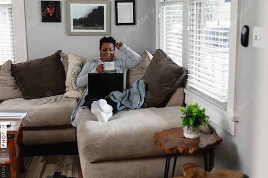 African American woman working from home on laptop drinking coffee