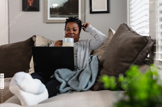 African American woman working from home on laptop drinking coffee