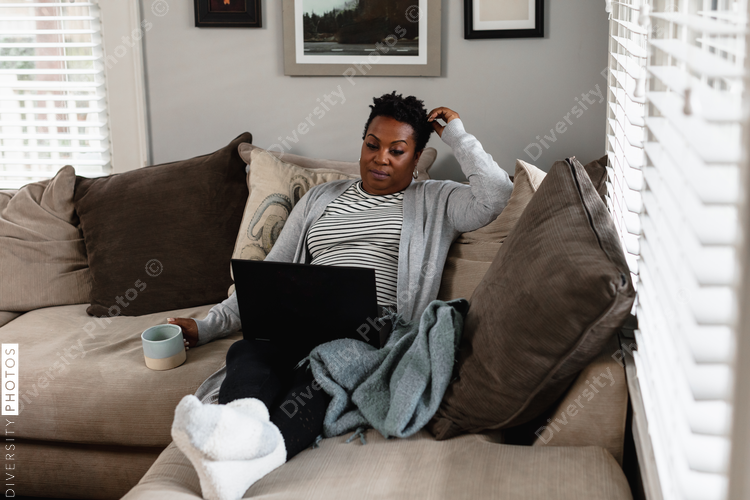 African American woman working from home on laptop drinking coffee