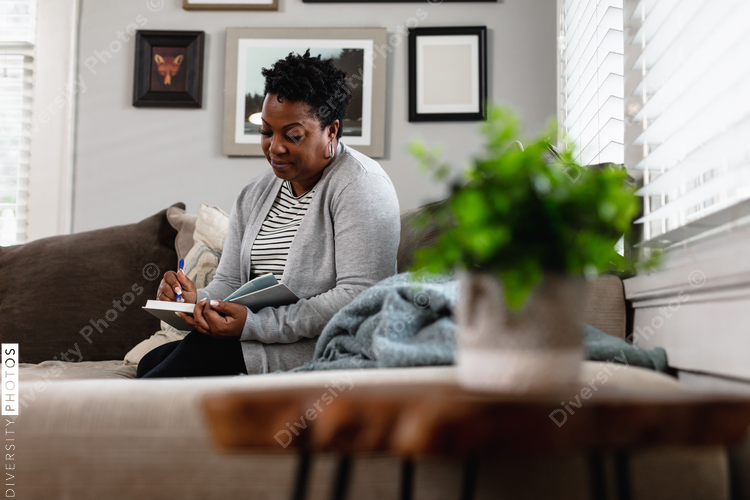African American woman writes in her journal at home in living room