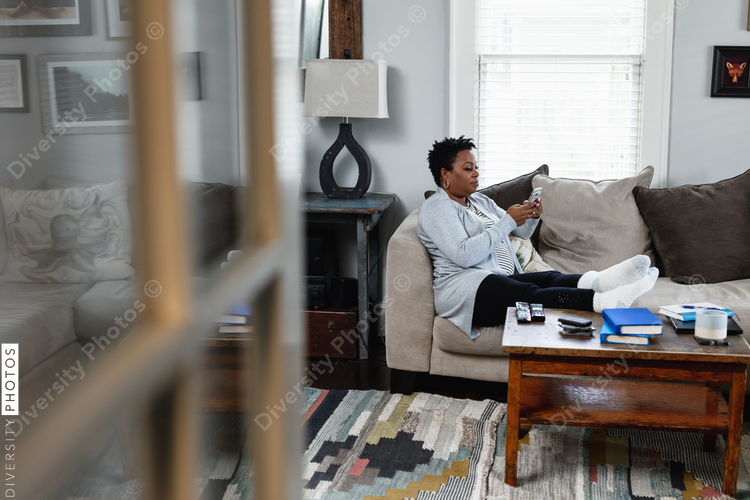Woman sits on couch while sending messages on phone