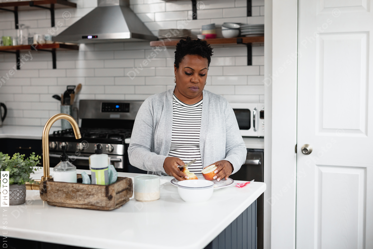Black woman prepares a lite snack in the kitchen
