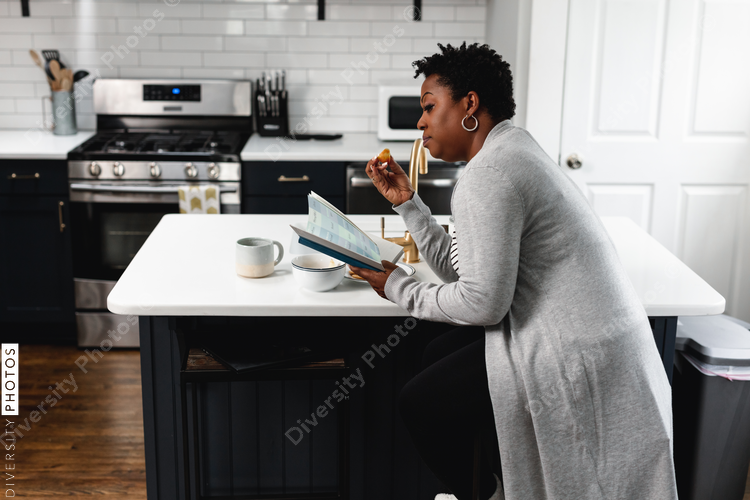 Black woman reading and eating in kitchen