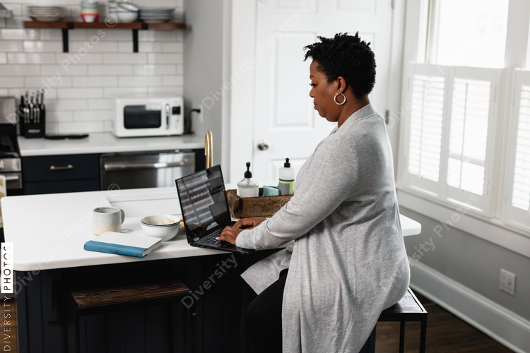 Black woman working from home at kitchen counter, on laptop