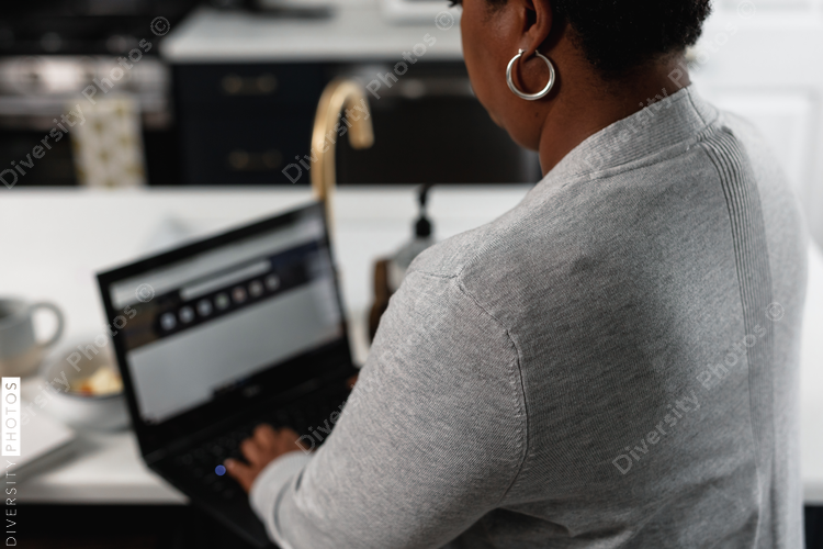 Black woman working from home at kitchen counter, on laptop