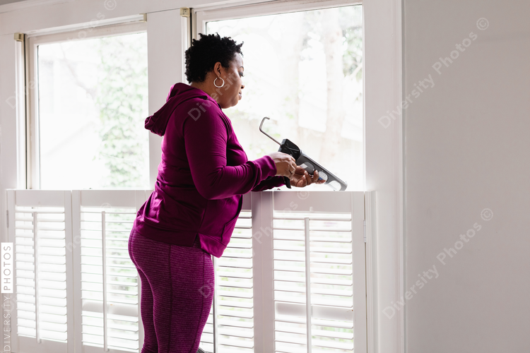 Black woman caulks window sill, energy efficiency, home improvement, DIY