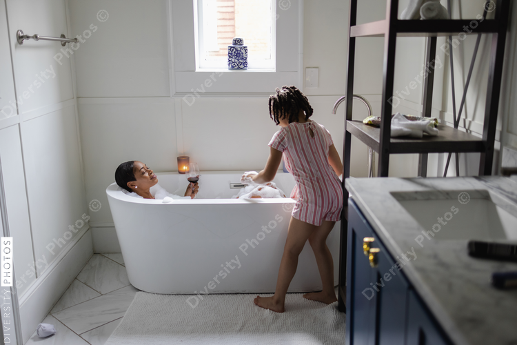 Daughter looking at mother taking bath