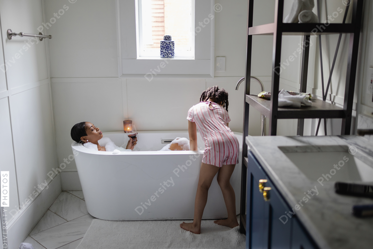 Daughter standing by mother taking bath