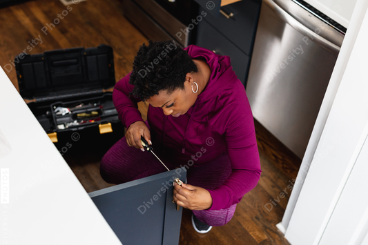 Black woman does DIY home repair on kitchen cabinet