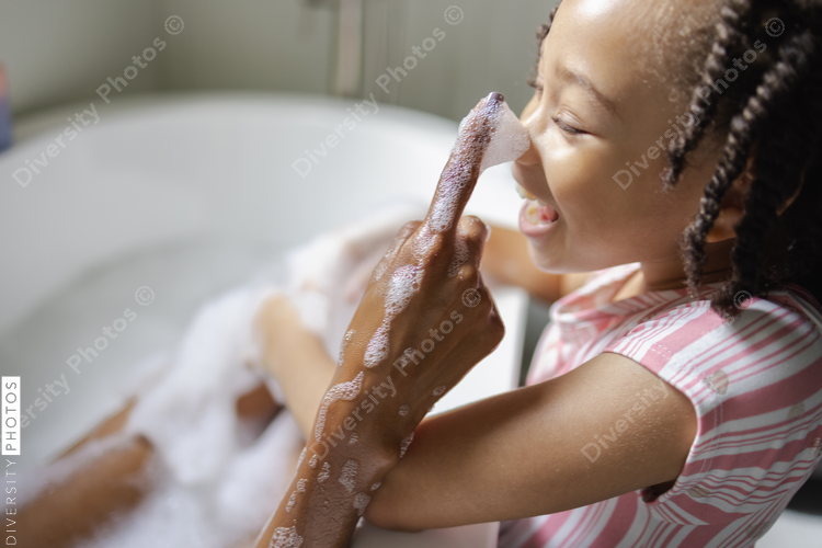 Mother taking bath putting soap on daughters nose