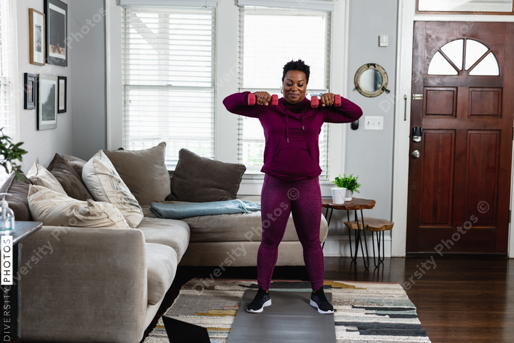 Black woman exercises while watching online tutorial fitness class