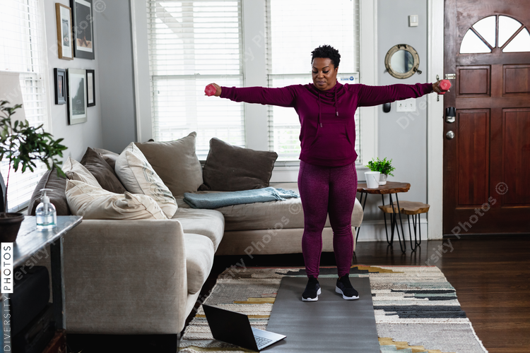 Black woman exercises while watching online tutorial fitness class