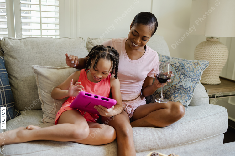 Mother and daughter sitting on sofa looking at tablet