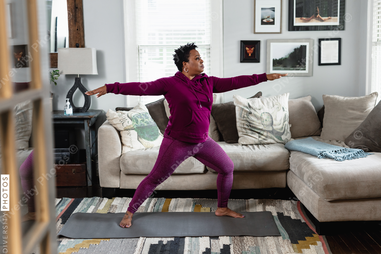Black woman does warrior yoga pose, at home fitness and wellness