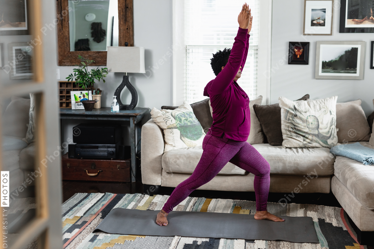 Black woman does warrior yoga pose, at home fitness and wellness