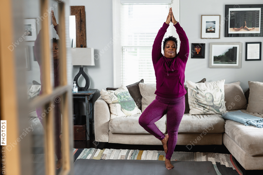 Black woman does tree yoga pose, at home fitness and wellness, centered strength