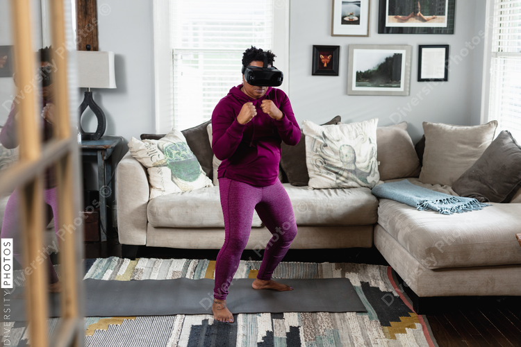 African American woman doing virtual reality VR boxing at home in living room