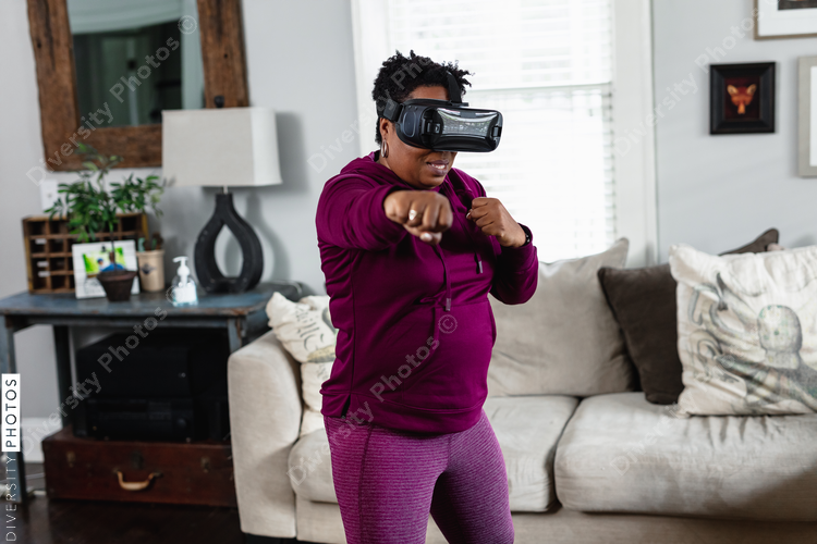 African American woman doing virtual reality VR boxing at home in living room