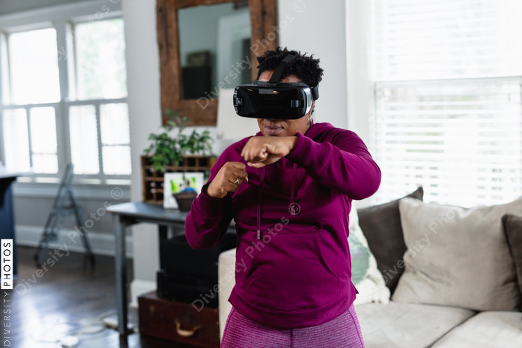 African American woman doing virtual reality VR boxing at home in living room