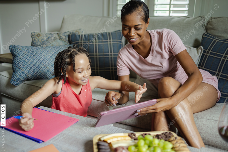 Mother and daughter using digital tablet at home