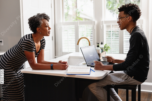 Black mother talking with son in kitchen at home