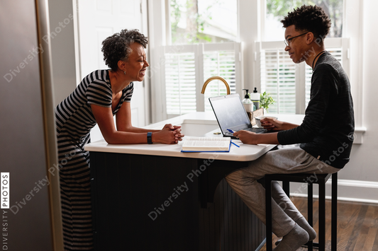 Black mother talking with son in kitchen at home
