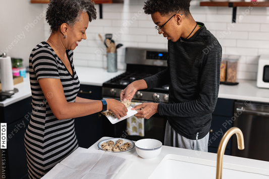 African American Mother and son preparing homemade baked cookies in kitchen