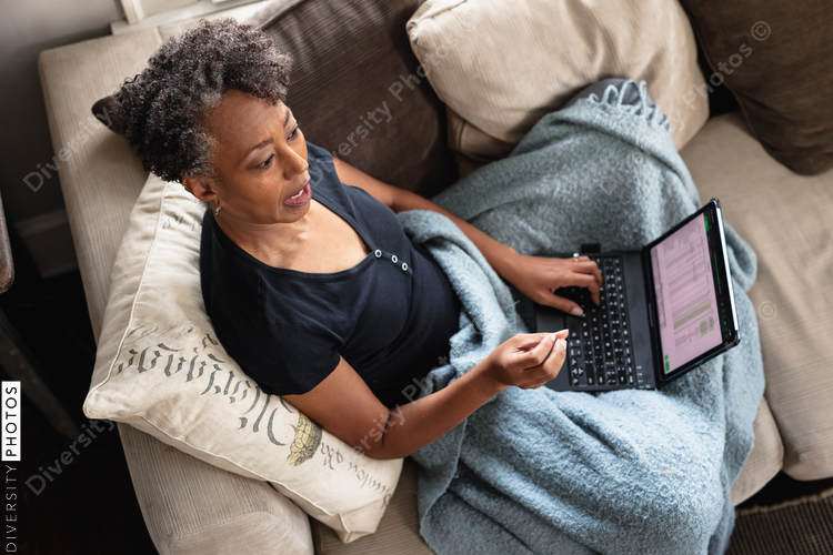 Overhead view of mature woman working from home on laptop, cozy and comfortable