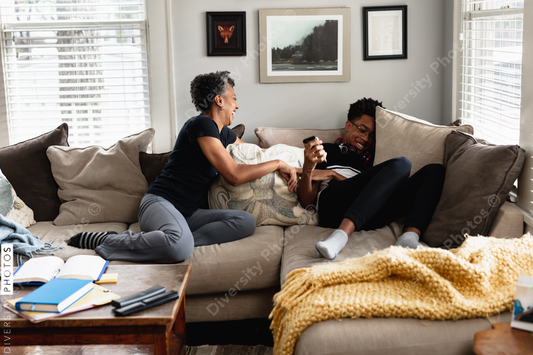 Black mother and son laughing together on couch, loving moment
