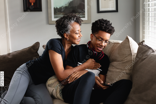 Black mother and son laughing together on couch, loving moment