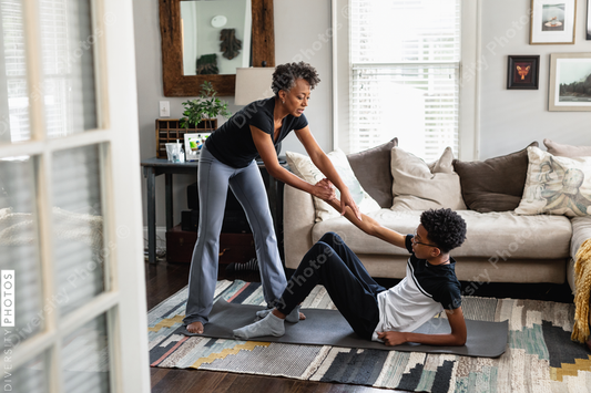 Black mom helps son up off the floor, after at home workout exercise