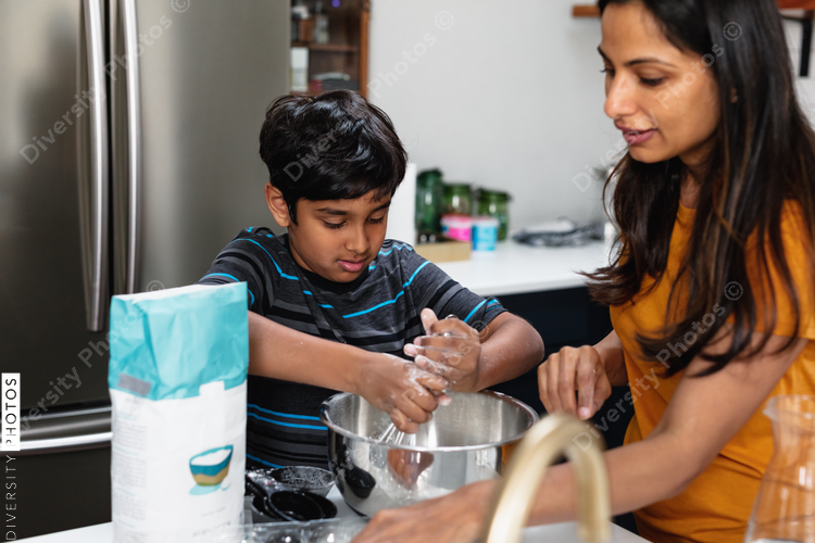 Indian mother and son baking in kitchen, having fun