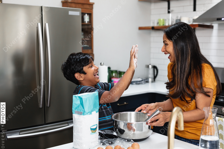 Indian mother and son baking in kitchen, having fun