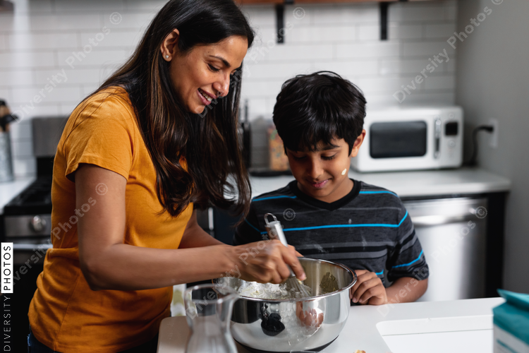 Indian woman and son bakes homemade cookies at home in kitchen