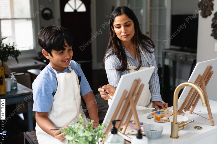 DIverse mother and son painting at home, kid activities