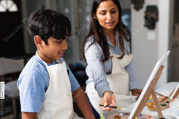 DIverse mother and son painting at home, kid activities