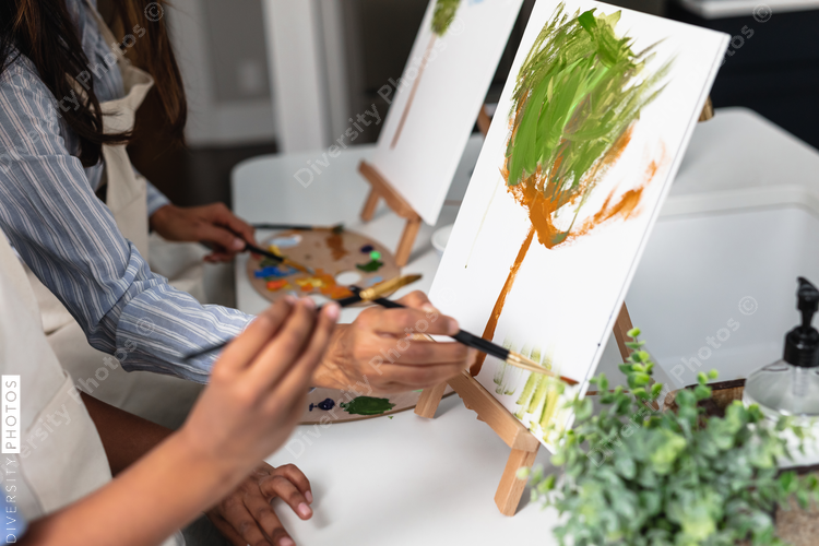 DIverse mother and son painting at home, kid activities